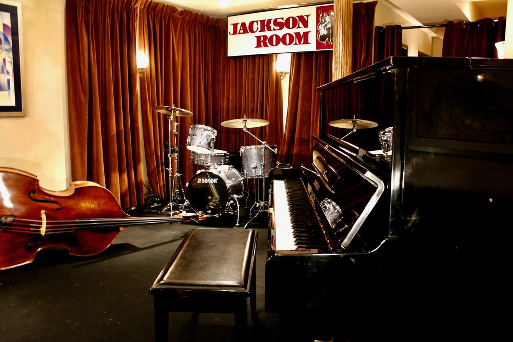 The stage of the Jackson Room with a Piano, Bass and Drums